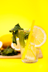 Fresh detox lemon water made of organic fruits on yellow background