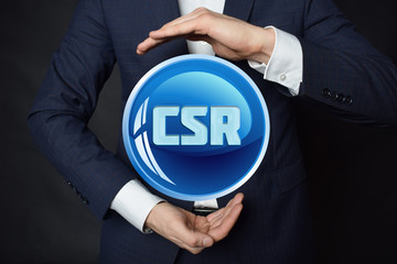 In the hands of a businessman, a neon circle with the inscription:CSR