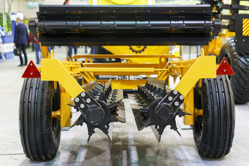 Agricultural machinery in agricultural fair. New agricultural machinery at the exhibition. Plow modern tech red tractor close up on an agricultural field. Mechanism.
