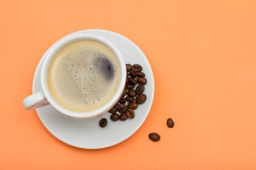 Cup of coffee and coffee beans on peach background