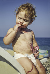 Baby boy covered with icecream on the beach