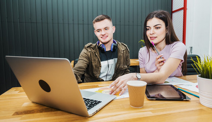 Two colleagues discussing the idea of the project, good-looking boy explaining the main point to lovely brunette, sitting on leather chairs at office desk