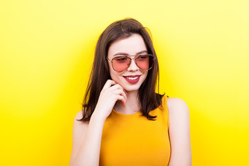 Sexy woman wearing sunglasses on yellow background