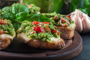 Bruschetta with fresh pesto, mozzarella and cherry tomatoes on cutting board