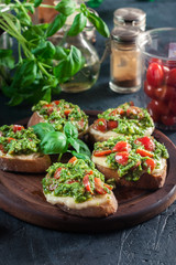 Bruschetta with fresh pesto, mozzarella and cherry tomatoes on cutting board