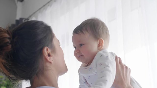 Happy mother with her baby playing together at bedroom
