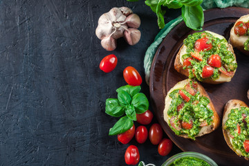 Bruschetta with fresh pesto, mozzarella and cherry tomatoes on cutting board