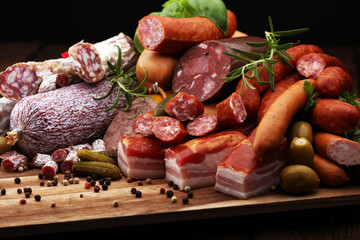 Food tray with delicious salami, ham,  fresh sausages, cucumber and herbs. Meat platter