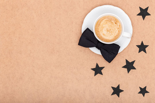Happy Father's Day Background. Cup of coffee and black bow tie on brown background flat lay. Fathers day still life.
