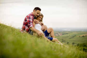 Loving couple sitting  hugged on grass in the mountain