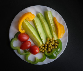 Various vegetables on a plate - cucumbers, tomatoes, paprika and pea.