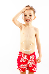 Child boy portrait in swimming pants with sunscreen on stomach.