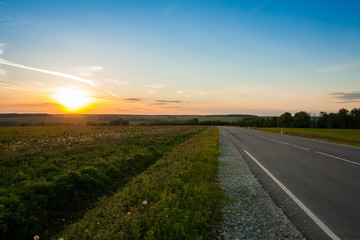 Beautiful Landscape With Asphalt Road Way On Sunset Of Sun Over Agriculture Fields In Spring.