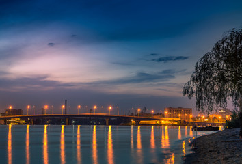 Obraz premium beautiful background sunset on the river with views of the illuminated lights Bridge