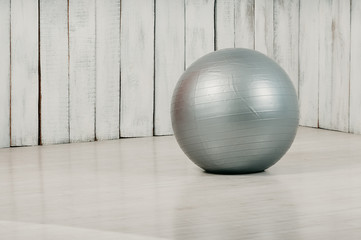 Grey fitball in a gym, light floor and background