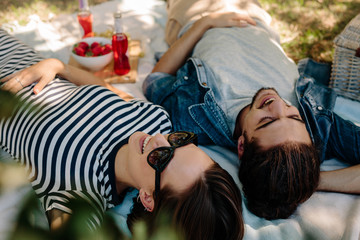 Cheerful couple on picnic at park - obrazy, fototapety, plakaty
