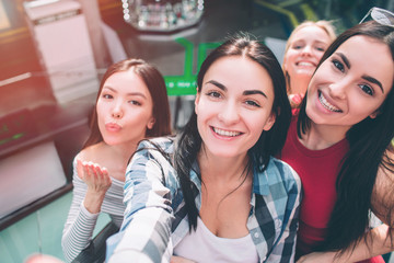 Selfie of four girls having fun together. They are posing with smile and sending kisses to camera.