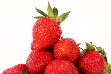 one fresh strawberry on top of a heap of strawberriws in the studio