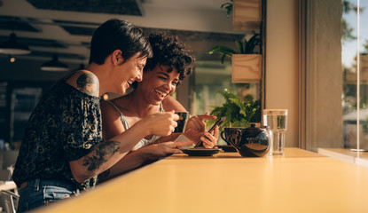 Friends in coffee shop looking at cellphone