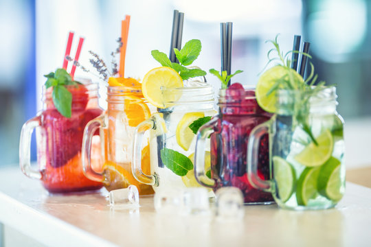 Various lemonades in mason jars with orange lime lemon otange strawberries and fresh fruit fruits