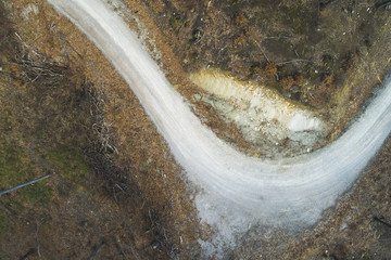 aerial Drone flight over forest and dirt road in a forest in Austria in march