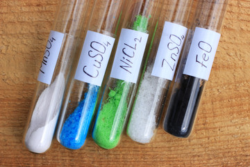 Chemical reagents in test tubes: nickel chloride, zinc sulfate, manganese sulfate, copper sulfate, iron oxide of black color.