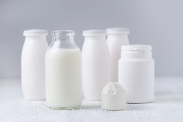 milk in a glass jar, milk powder and drink yogurt on the table, gray background