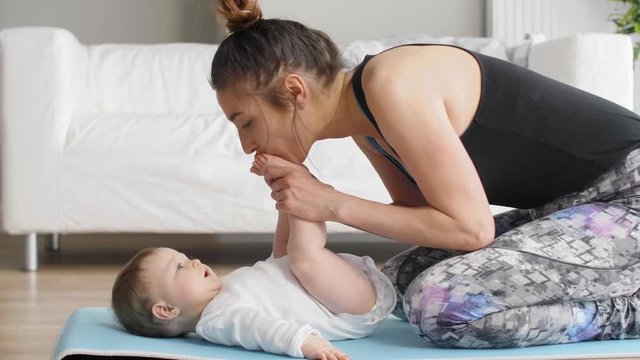 Cheerful woman exercising with her baby girl at home