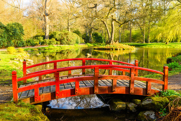 Krapperup, Sweden - Red wooden bridge over a small stream in a park in spring.