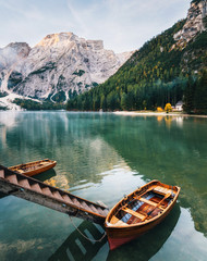 Boats and slip construction in Braies lake with crystal water in background of Seekofel mountain in Dolomites in morning, Italy Pragser Wildsee