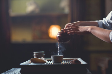 Fototapeta na wymiar Female hands pouring tea from teapot