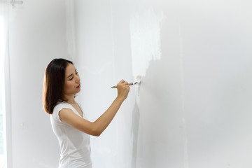 Young Asian woman painting on a white wall