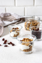 Bowl of homemade muesli with nuts, berries, dried fruits, milk and honey on white wooden background. Healthy breakfast. top view