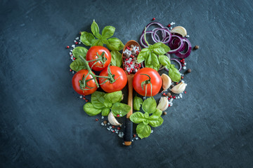 Tomatoes Basil Garlic and spices on a stone table in the form of heart healthy food Concept.