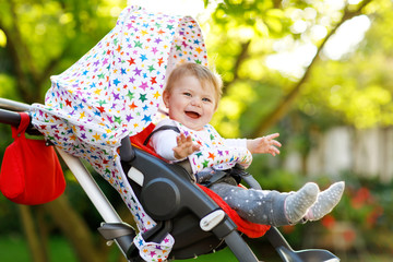 Cute little beautiful baby girl of 6 months sitting in the pram or stroller and waiting for mom