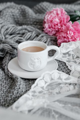 Obraz na płótnie Canvas A cup of coffee and peonies on a gray plaid