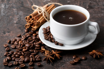 Coffee beans and cinnamon on a background of burlap. Roasted coffee beans background close up. Coffee beans pile from top with copy space for text. Seasoning. Spice. Cinnamon. Badian. Coffee house.