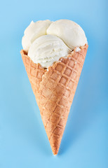ice cream balls with colored sugar sprinkles in a Waffle Cone on a Blue Background. Vanilla ice cream in a waffle cone.