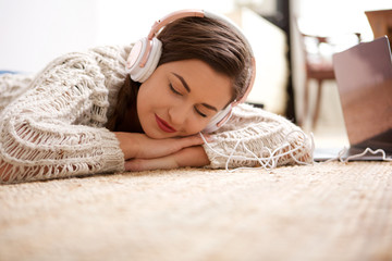 young woman sleeping on floor and listening to music with headphones