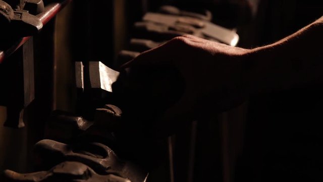 Close-up of a man's hand throws a hammer and rotates it on a dark background in the contour light. Brutal powerful concept