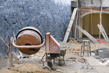 Cement mixer machine at construction site, tools, sand and cement bag. Construction concept.