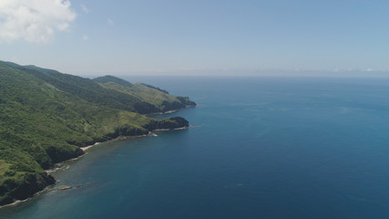 Coast of a tropical island Palau with mountains covered with rainforest and trees. Santa Ana, Philippines. Aerial view of island with wild beaches.