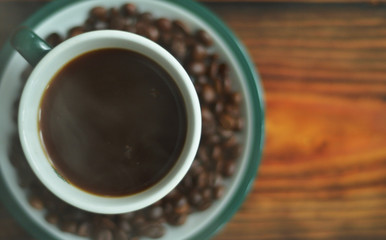 A cup of coffee on a saucer with fried coffee beans