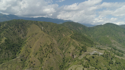 Aerial view of rice fields and agricultural land on the slopes of the mountains. Mountains covered forest, trees. Cordillera region. Luzon, Philippines.