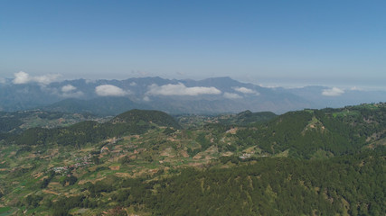 Aerial view of rice terraces and agricultural farm land on the slopes of mountains valley. Cultivation of agricultural products in mountain province. Mountains covered forest, trees. Cordillera region