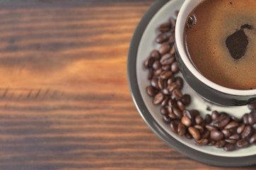 A green cup with coffee on a saucer with coffee beans