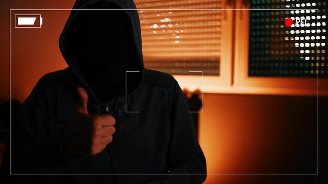 Hacker ransomware demands, computer crime and network security concept. Hooded male person recorded spoken list of requests to be paid as ransom for unlocking access to computer.