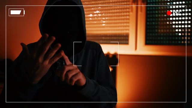 Hacker ransomware demands, computer crime and network security concept. Hooded male person recorded spoken list of requests to be paid as ransom for unlocking access to computer.