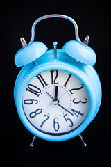 Blue alarm clock on black background