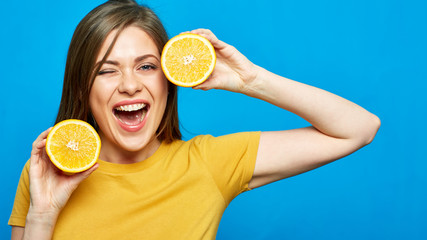 Cheerful girl holding two slices of orange.